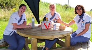 Verpleegkundigen AZ Sint-Maarten lunchen aan picknicktafel in de zon